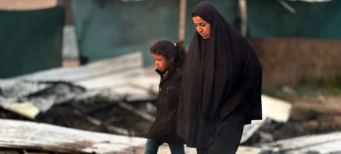 A woman and child walk through the rubble of Gaza.