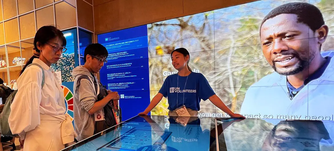 A UN Volunteers staff member explains the role of the organization to visitors at the UN Pavilion.