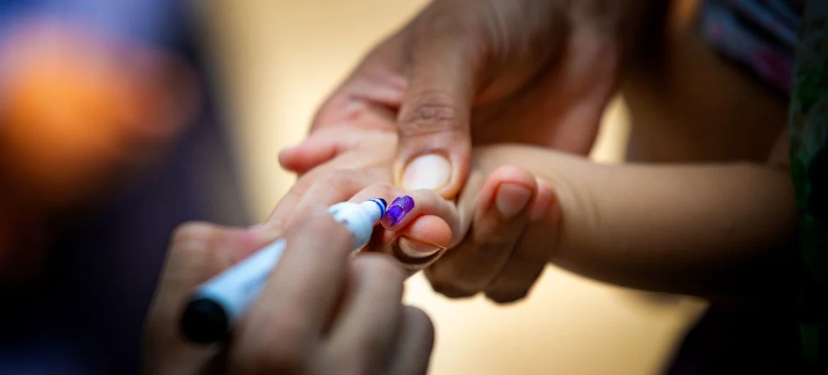 In Lahore, Pakistan, a health worker marks a baby's finger to show she has received the polio vaccine. 