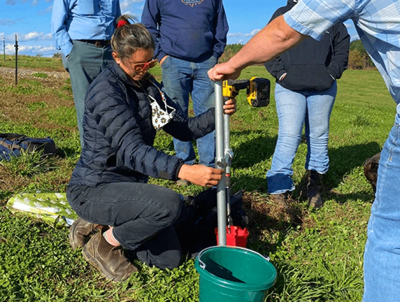 feature regenagcommit inline Leah Puro and Jason Johnson take a soil sample from a Dostie Farm pasture with an AgriCORE soil sampling tool while the Dosties and Brown look on. Credit: Meg Wilcox