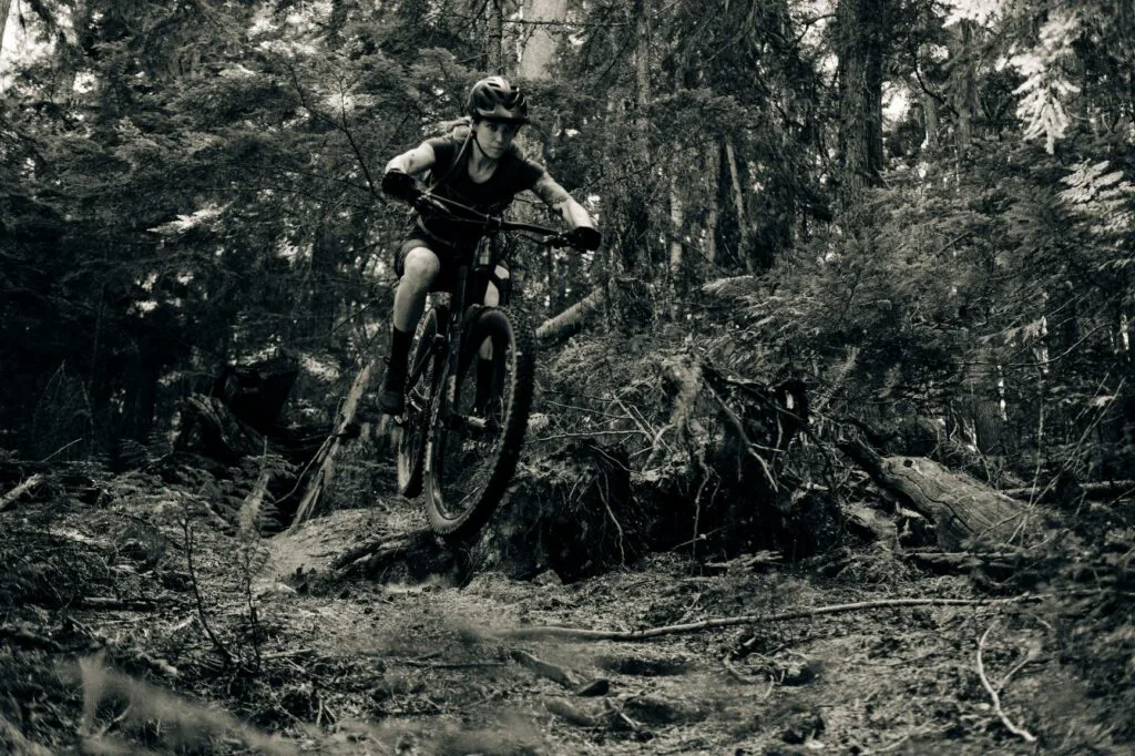 Woman mountain biking on a rugged, forested dirt trail in the Yaak wilderness of northwest Montana.