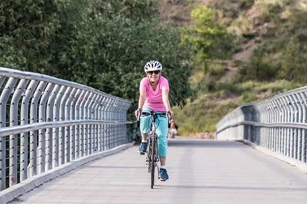 Photo of Lisa Brown biking across bridge.