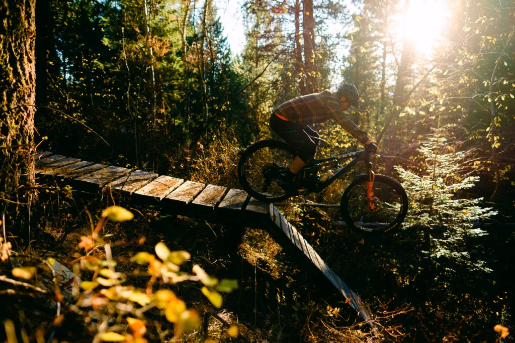 Mountain biker riding over a wooden bridge on a singletrack trail.