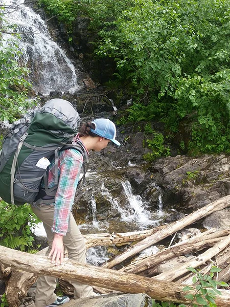 Photo of hiker traversing log jam.
