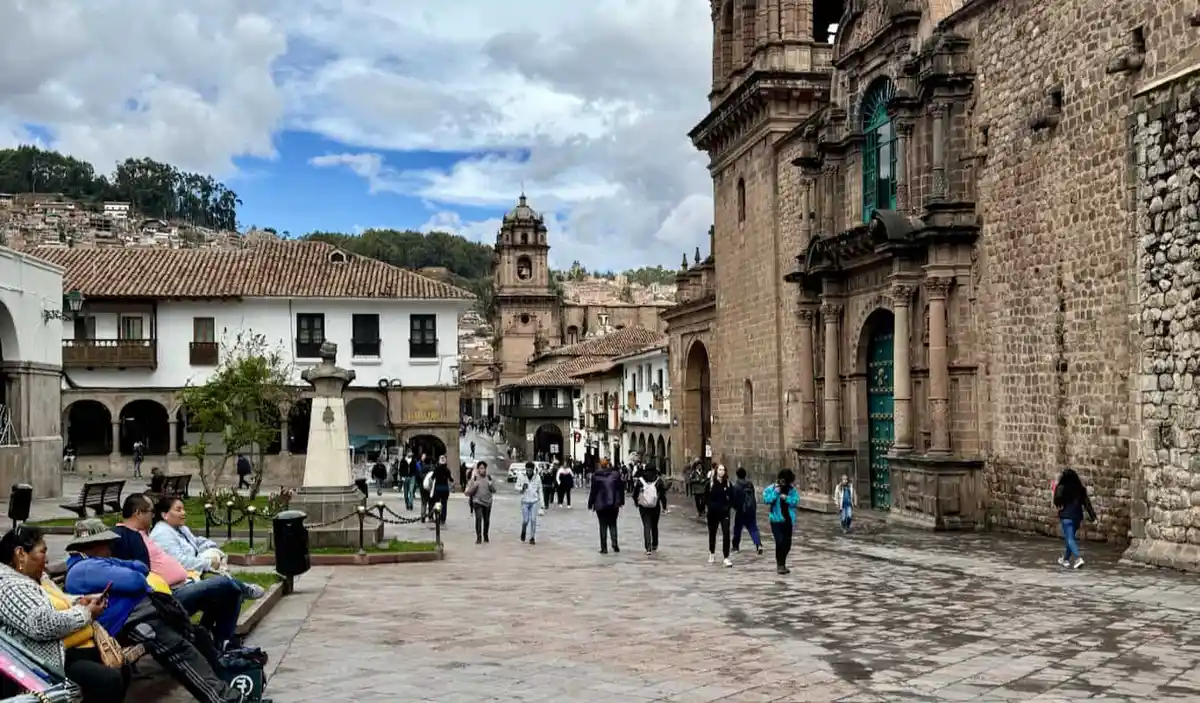 A historic plaza full of tourists and locals in sunny Cusco, Peru
