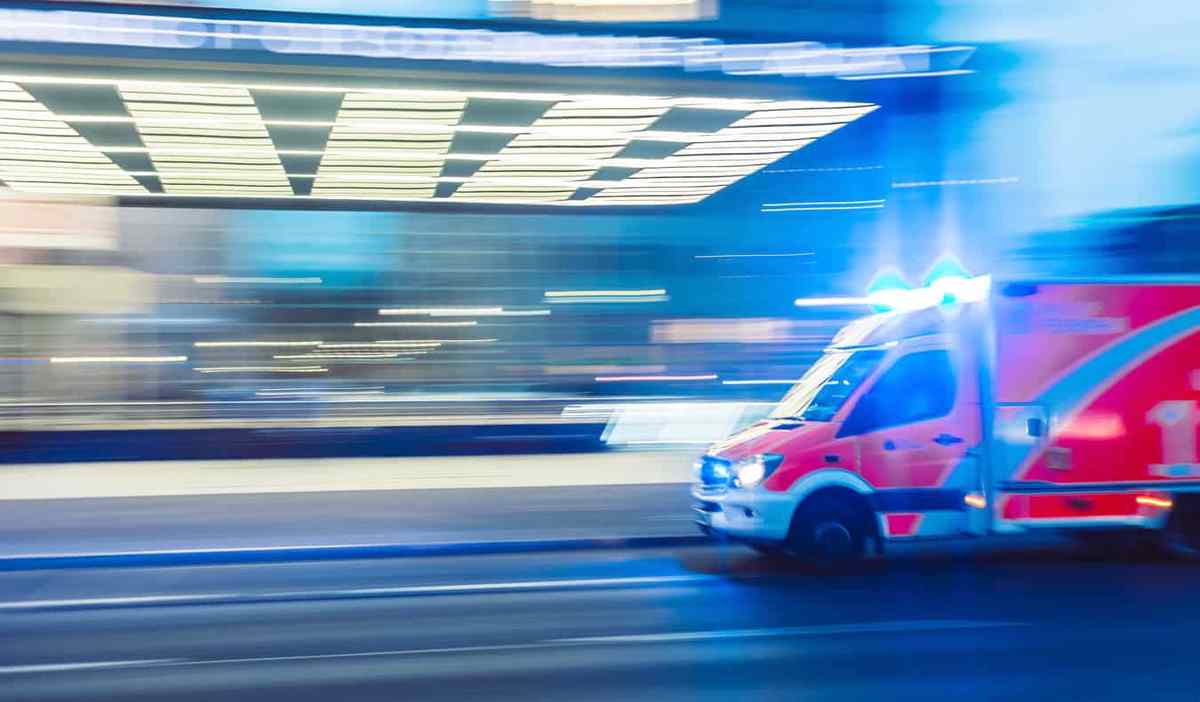 An ambulance driving quickly at night with flashing lights