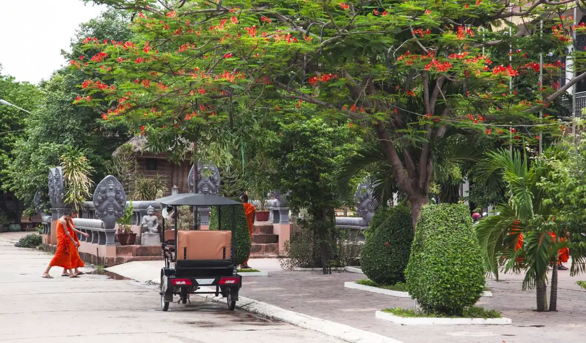 Monks walk down a street by a tuk tuk in Siem Reap, Cambodia