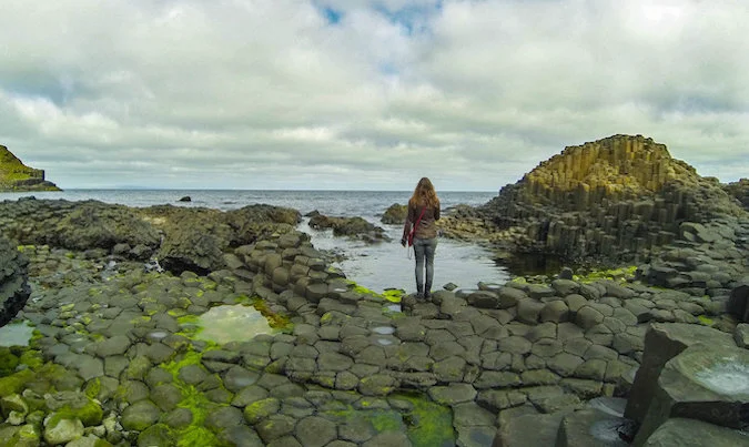 Solo female traveler looking at beautiful rocky Icelandic landscape near the ocean