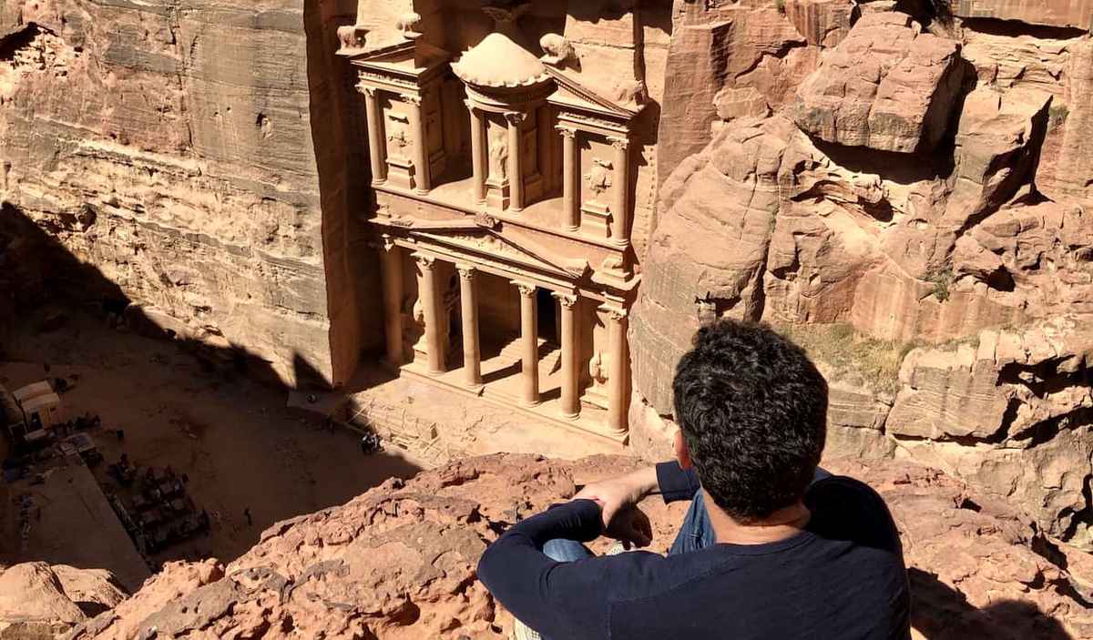 Nomadic Matt posing on a cliff looking out over Petra in Jordan