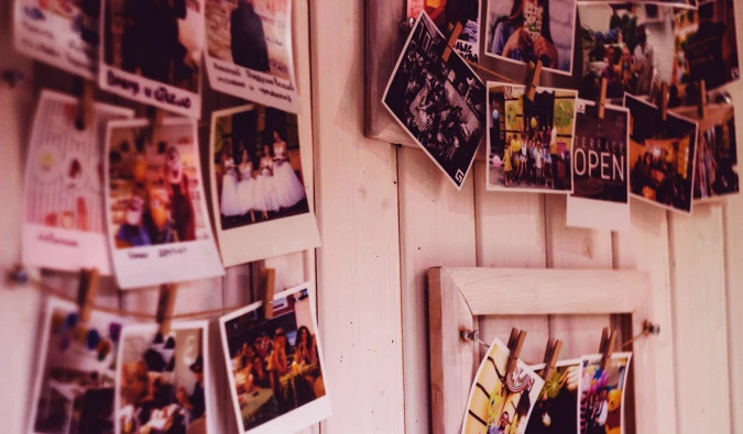 A bunch of old photos hanging on display against a wooden wall