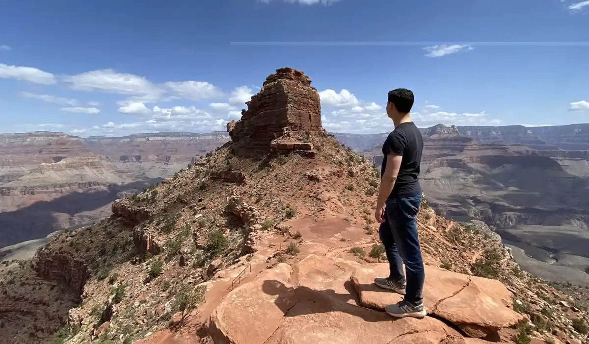 Nomadic Matt alone posing near some stunning rock formations while visiting the Grand Canyon