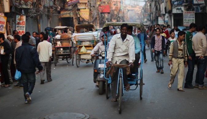 a busy street in an Indian city, full of people and rickshaws
