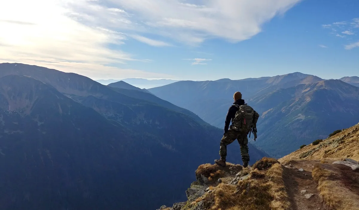 A solo traveler standing on the edge of a cliff looking in the distance