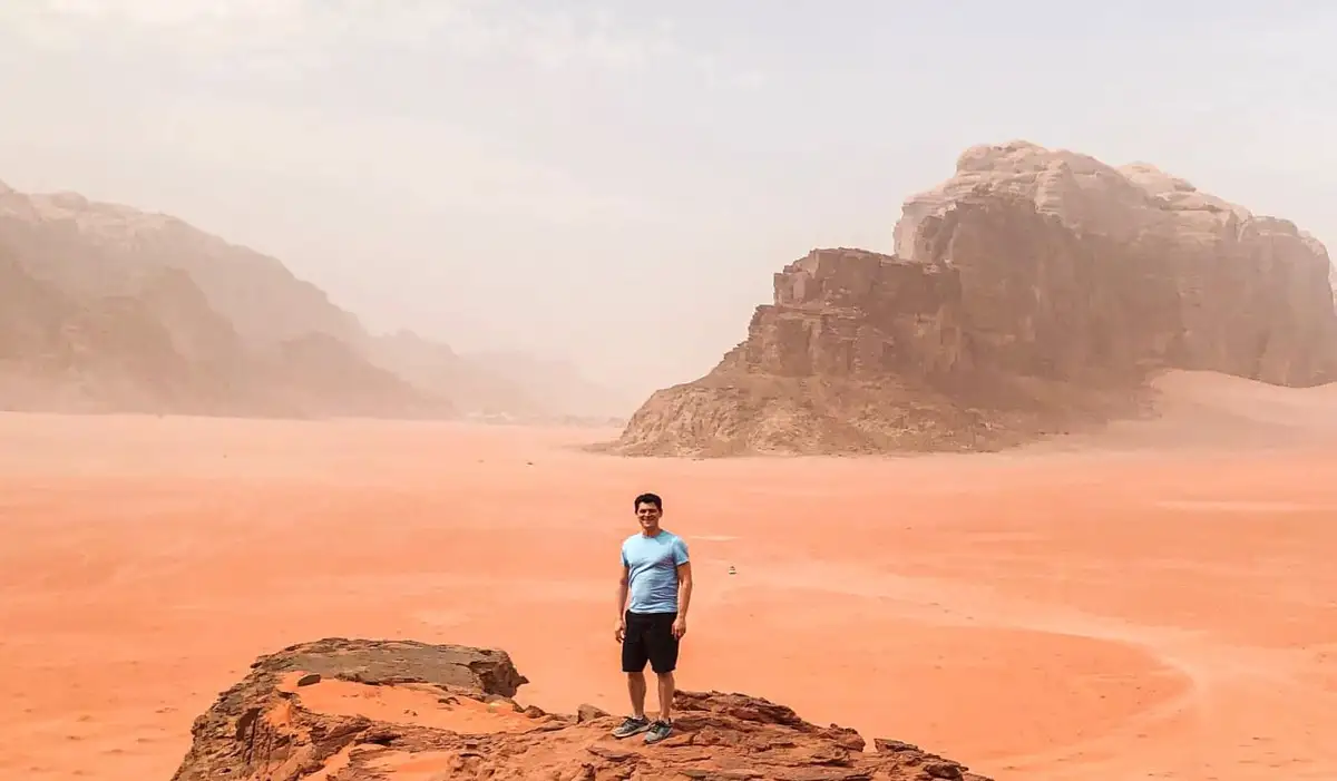 Nomadic Matt standing on a large rock formation in the desert in Jordan