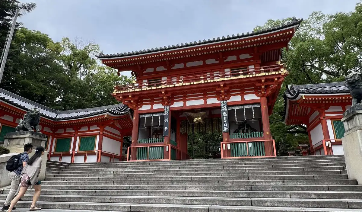 Two young students walking up the steps to the red Yasaka Shrine in Kyoto, Japan